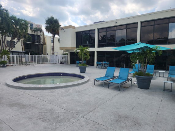 Outdoor area with a small circular pool, blue lounge chairs, and large windows on the building.