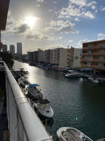 Panoramic view of a canal with boats and several multi-story buildings on both sides.