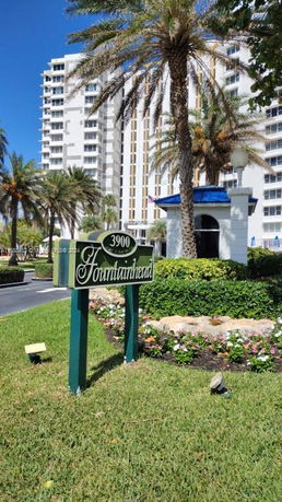 Front view of a multi-story building with palm trees and a sign reading 'Fountainhead'.