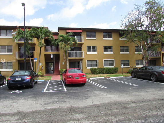 Front view of a three-story apartment building with a central staircase and surrounding balconied walkways.