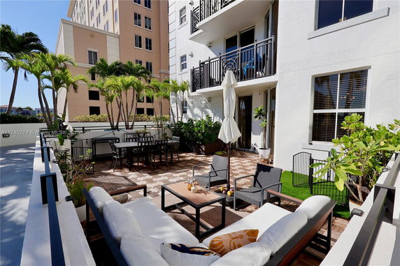 Outdoor terrace area with seating and dining, surrounded by buildings.