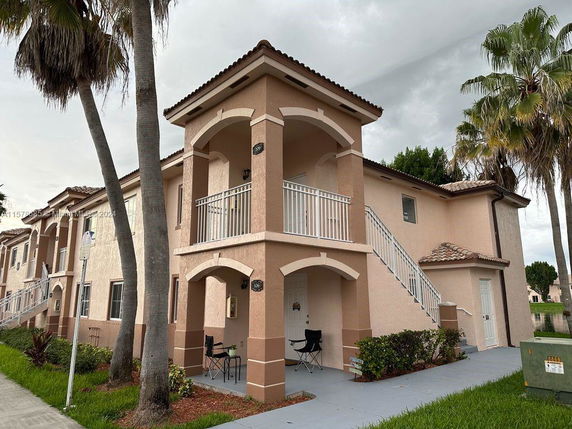 Front view of a two-story building with exterior stairs and covered balconies.