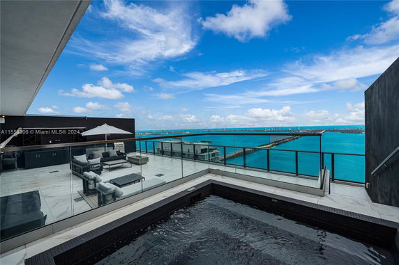 Rooftop area with seating, glass railing, and a view of the ocean.