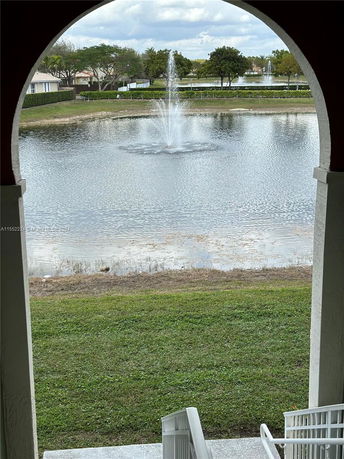 View from a building archway overlooking a pond with a fountain.