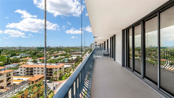 Panoramic view from a high balcony overlooking urban and suburban areas with buildings and greenery.