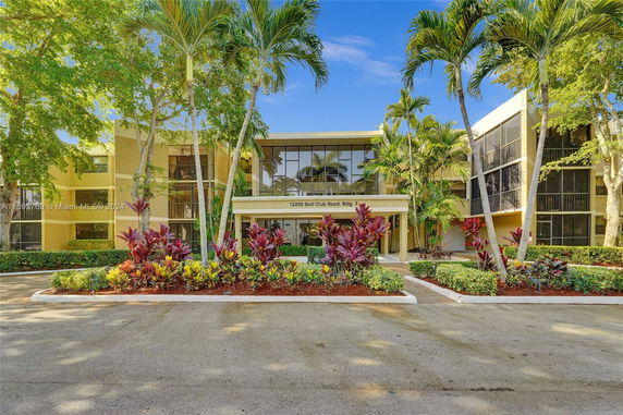 Front view of a multi-story building with large windows and landscaped entrance.