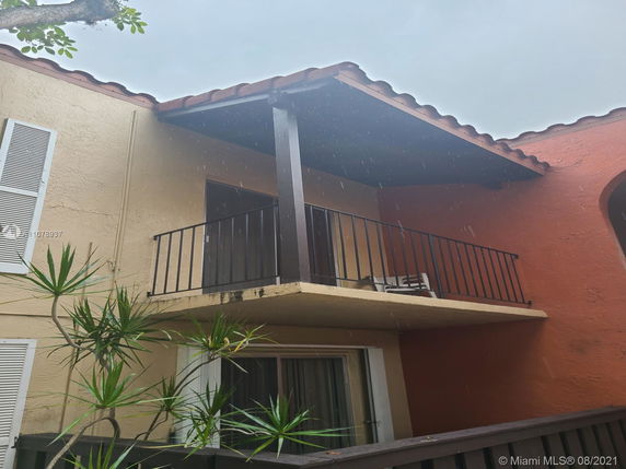 Front view of a two-story house with a balcony and slanted roof.