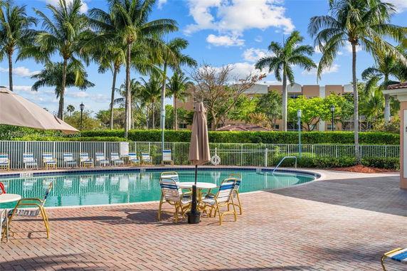 Outdoor swimming pool with lounge chairs and palm trees.