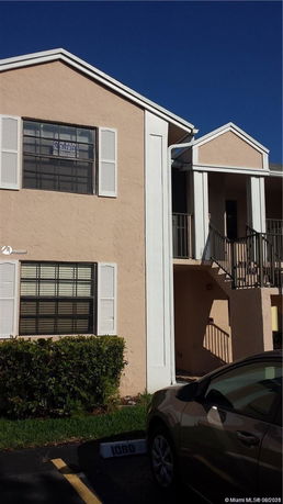 Front view of a two-story residential building with beige exterior and white trim.