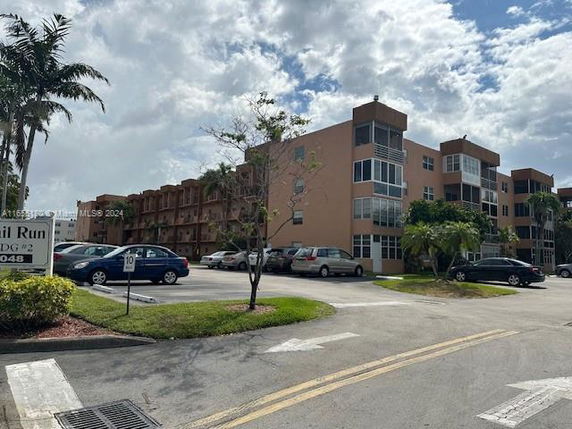 Front view of a multi-story residential building with balconies and parking area.