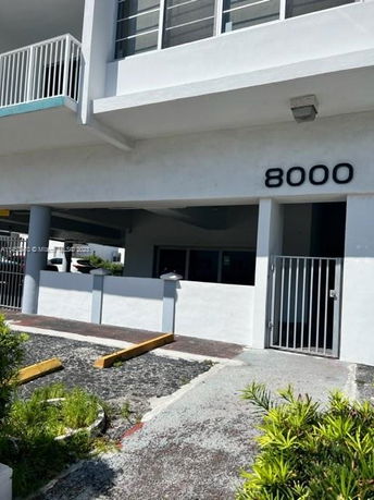 Front view of a multi-story building with metal gates and a visible number 8000 on the facade.