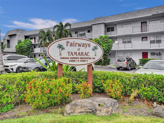 Front view of a multi-story condominium building with parking area in front.