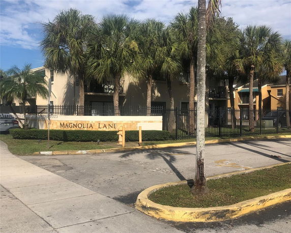 Front view of a multi-story residential building with palm trees in front.