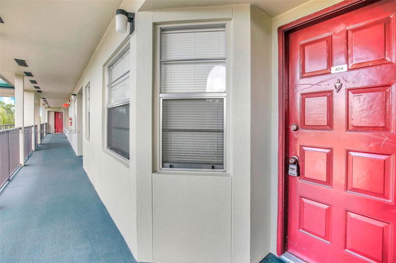 Exterior corridor of a residential building with red doors and windows.