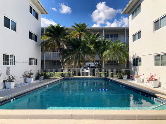 Outdoor swimming pool surrounded by multi-story residential buildings.