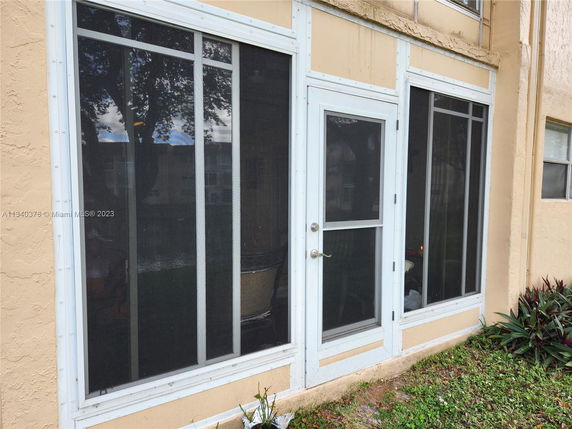 Exterior view of a building with a screened patio door and windows.