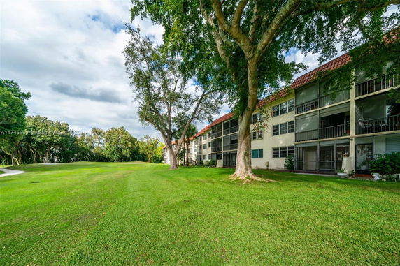 View of an apartment building with balconies and green lawn area.