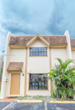 Front view of a two-story townhouse with a gabled roof and large windows.