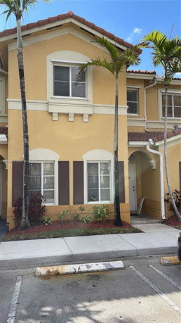 Front view of a two-story house with yellow exterior and brown shutters.