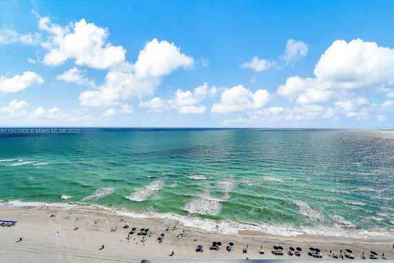 Panoramic view of a beach and ocean with umbrellas set up on the sand.