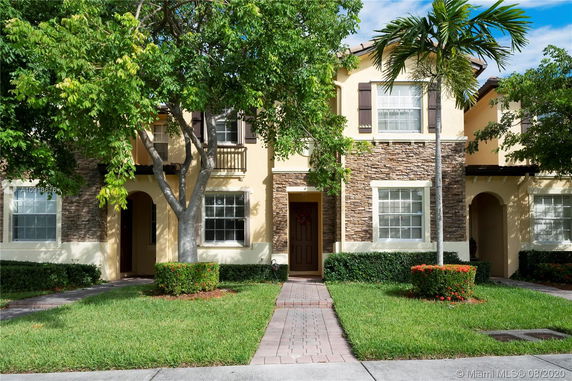 Front view of a two-story house with stone facade and arched entrance.