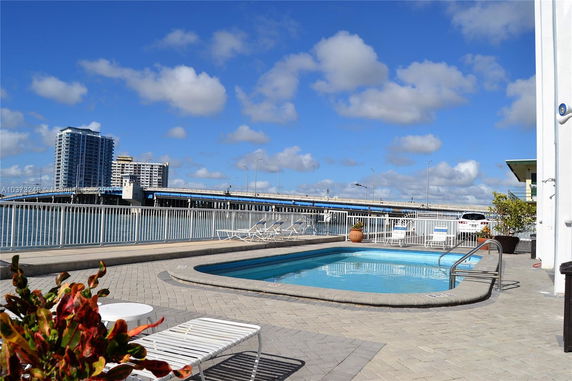 View from a poolside area showing nearby high-rise buildings and a bridge over water.