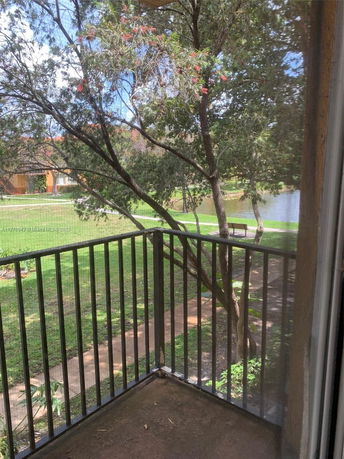 View from a balcony overlooking a grass area with trees and a path.