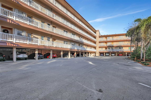 Outdoor parking area beneath a multi-story residential building with balconies.