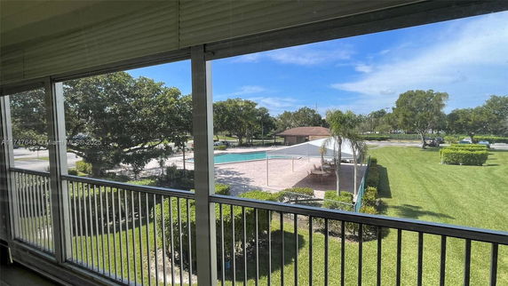 View from a balcony overlooking a swimming pool and landscaped area.