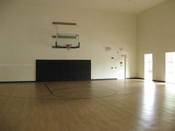 Indoor basketball court with wooden flooring and a basketball hoop.