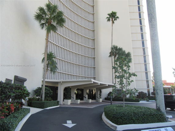 Front view of a multi-story building with a curved facade and a covered entrance.
