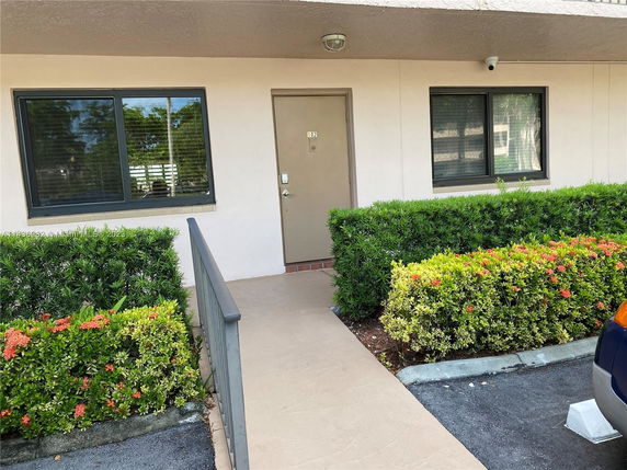 Front view of a building entrance with two windows and a pathway leading to the door.