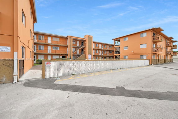 Front view of a multi-story apartment building with orange exterior and balconies.