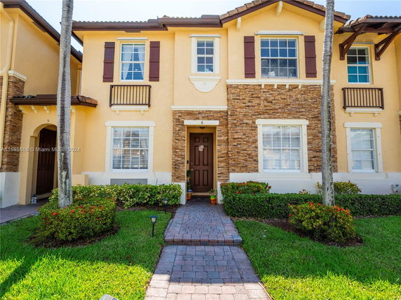 Front view of a two-story house with a light-colored exterior and decorative stone accents.