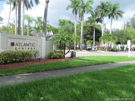 Entrance of Atlantic Springs with palm trees and landscaping.