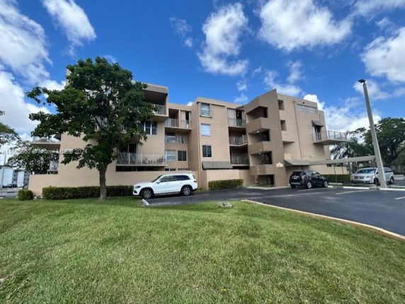 Front view of a multi-story apartment building with balconies and parking area.