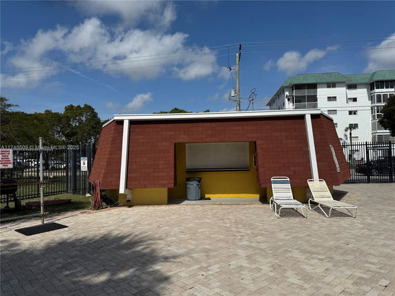 Outdoor view of a small building near a swimming pool area with sun loungers.