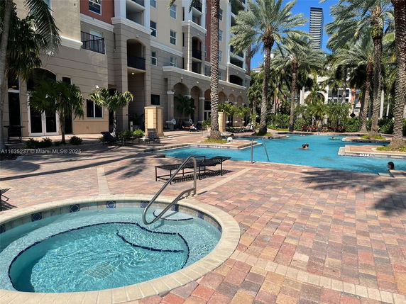 Outdoor swimming pool area with adjacent hot tub and palm trees.