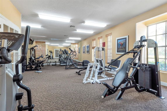 Indoor gym area with various exercise equipment and large windows.