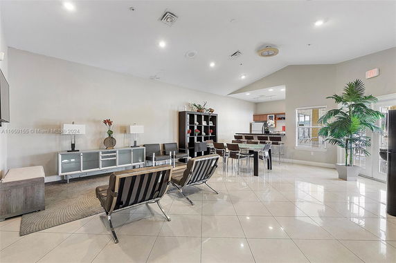 Interior view of a community recreation area with seating, tables, and a kitchenette.