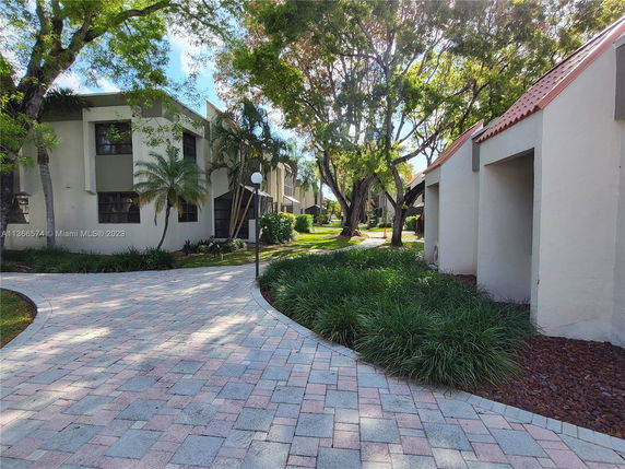 Front view of a multi-story building with a paved walkway and trees.
