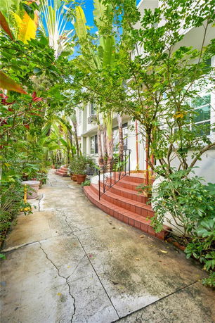 Front view of a building with red brick steps and lush greenery.