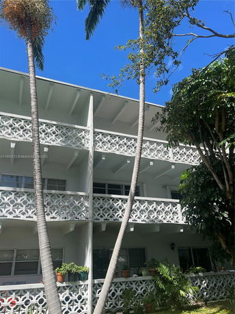 Front view of a multi-story building with decorative balconies and surrounding trees.