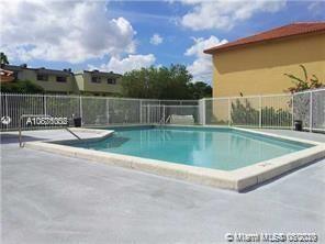 Outdoor swimming pool area with fencing and nearby buildings.