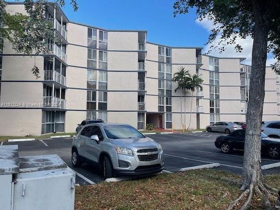 Side view of a multi-story apartment building with a parking area in front.