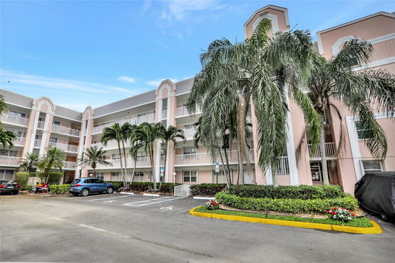 Front view of a multi-story residential building with balconies and palm trees.