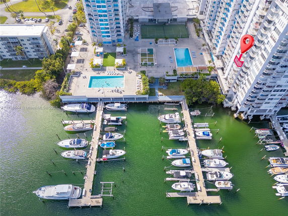 Aerial view of high-rise buildings with swimming pools and marina docks with boats.