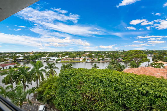 Panoramic view of a residential area near a water body with lush greenery and clear blue sky.