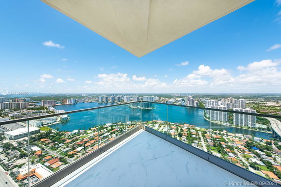 Panoramic view from a building's balcony overlooking a cityscape and water body.