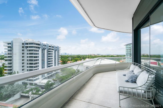 Panoramic view from a balcony overlooking modern buildings and greenery.